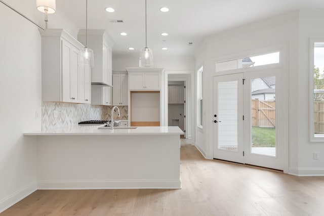 kitchen with sink, white cabinets, light hardwood / wood-style floors, and decorative light fixtures