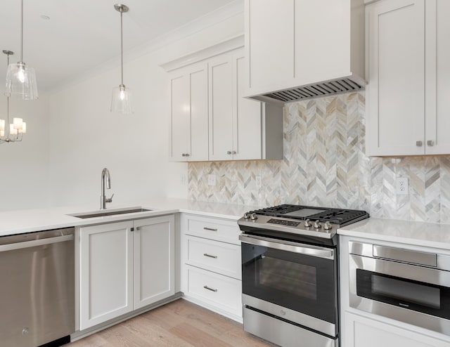 kitchen with sink, hanging light fixtures, light hardwood / wood-style flooring, white cabinets, and appliances with stainless steel finishes