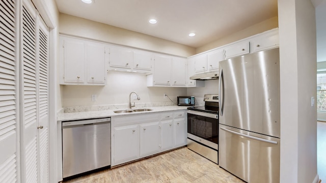 kitchen with light stone countertops, white cabinetry, sink, and stainless steel appliances