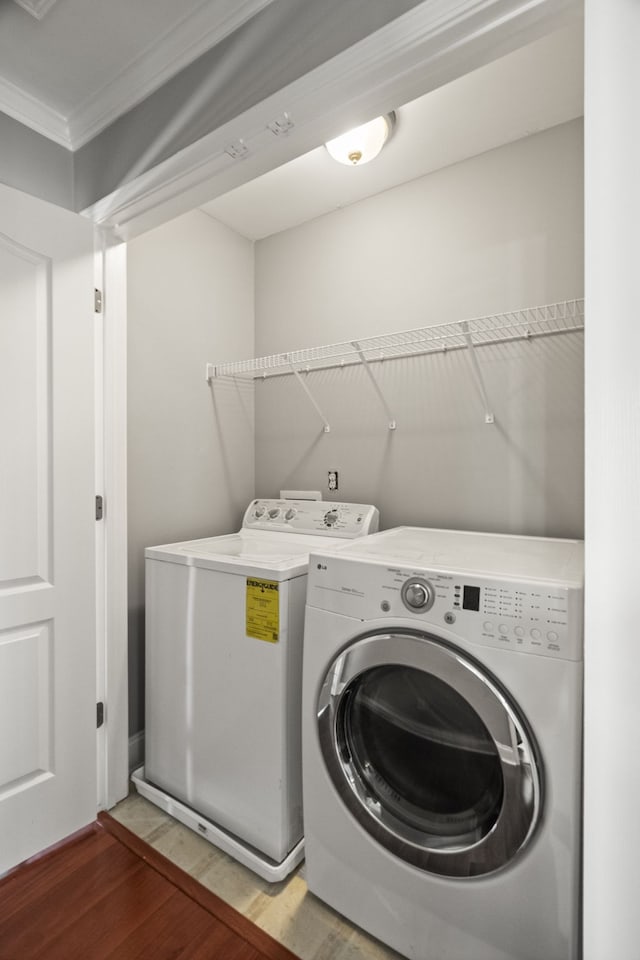 laundry area featuring washer and dryer, wood-type flooring, and ornamental molding