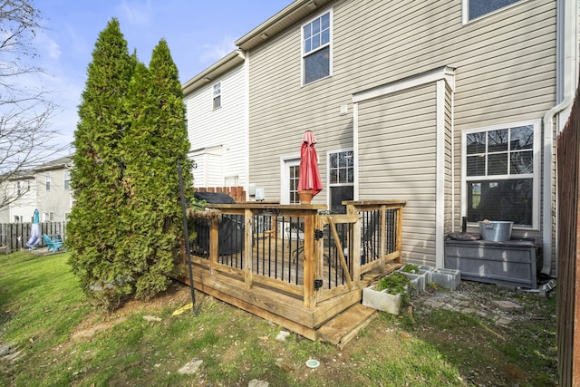 rear view of property featuring a deck and a lawn