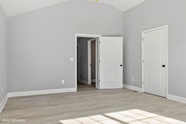 unfurnished bedroom with light wood-type flooring and high vaulted ceiling