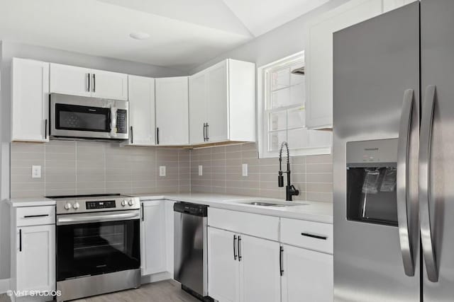 kitchen featuring tasteful backsplash, white cabinetry, sink, and appliances with stainless steel finishes