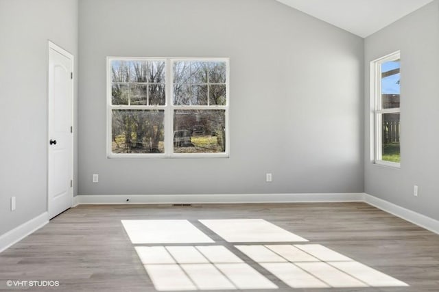 unfurnished room with lofted ceiling, a healthy amount of sunlight, and light wood-type flooring