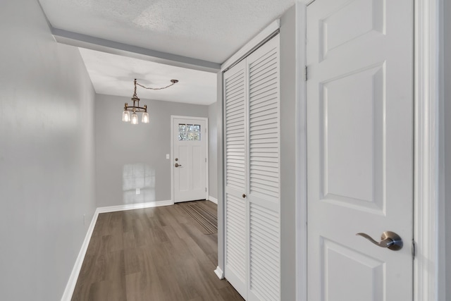 hall featuring hardwood / wood-style floors, a textured ceiling, and an inviting chandelier