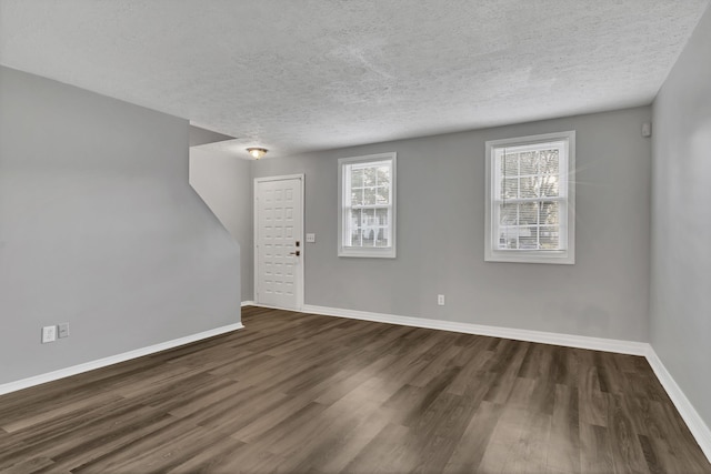 unfurnished room with dark hardwood / wood-style flooring and a textured ceiling