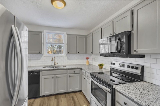 kitchen with light wood-type flooring, backsplash, sink, black appliances, and gray cabinets