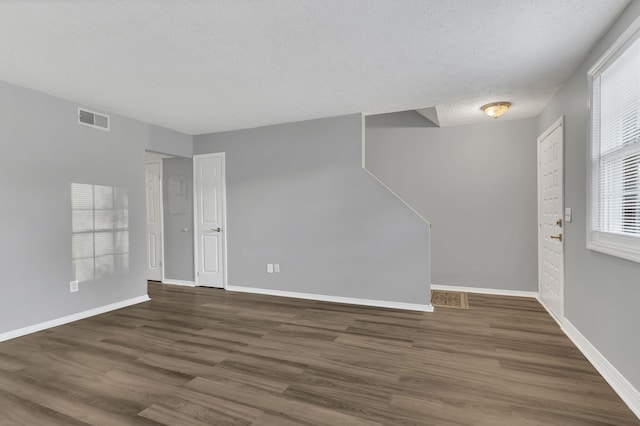 unfurnished room featuring dark hardwood / wood-style flooring and a textured ceiling