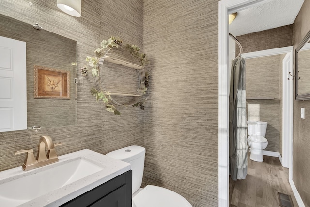 bathroom with toilet, vanity, tile walls, and hardwood / wood-style flooring