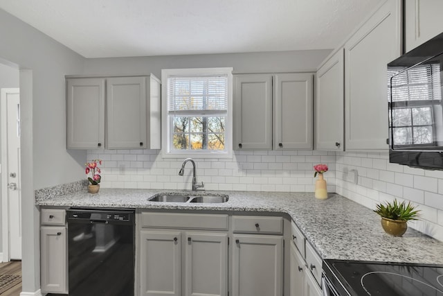 kitchen with sink, light stone counters, wood-type flooring, decorative backsplash, and black appliances