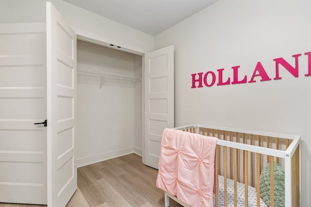 bedroom with light hardwood / wood-style flooring and a nursery area