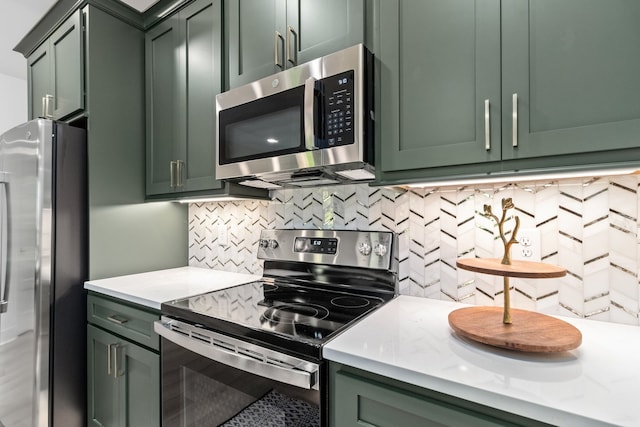 kitchen with backsplash, appliances with stainless steel finishes, and green cabinetry