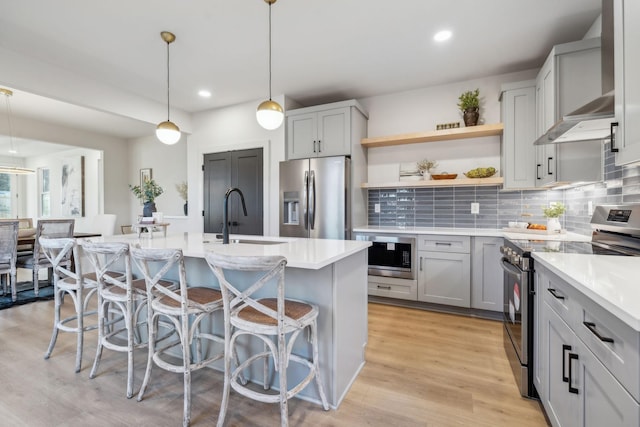 kitchen featuring appliances with stainless steel finishes, sink, pendant lighting, a breakfast bar, and an island with sink