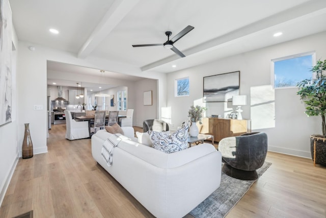 living room featuring ceiling fan, light hardwood / wood-style flooring, and beamed ceiling