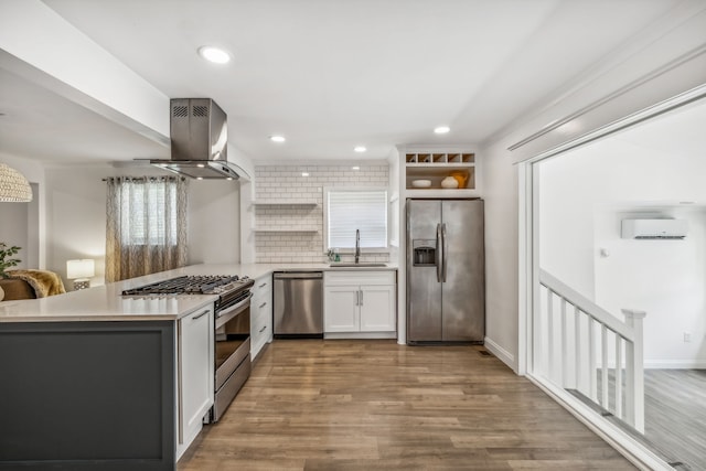 kitchen featuring kitchen peninsula, appliances with stainless steel finishes, a wall unit AC, white cabinetry, and range hood