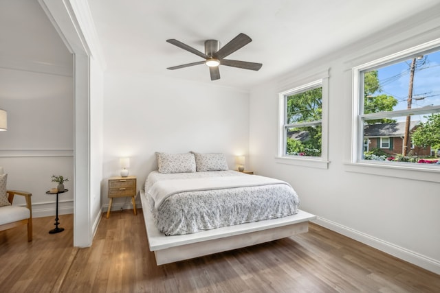 bedroom with hardwood / wood-style floors, ceiling fan, and ornamental molding