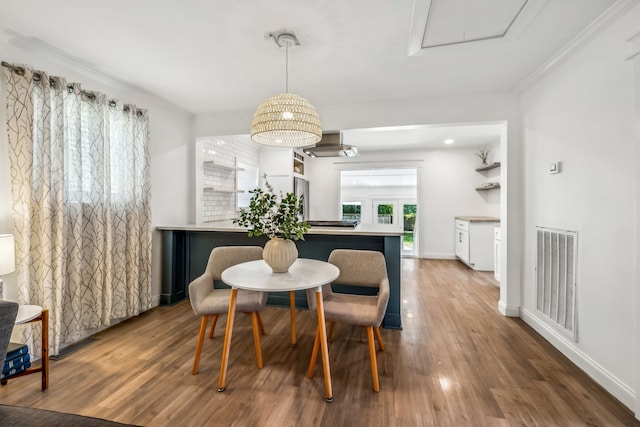 dining space featuring wood-type flooring and crown molding