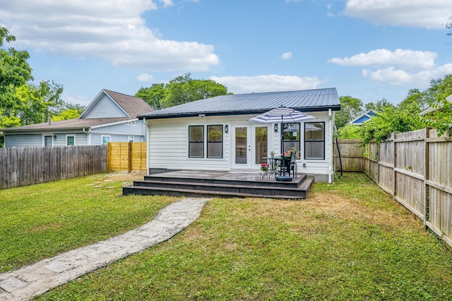 rear view of property featuring a lawn and a deck