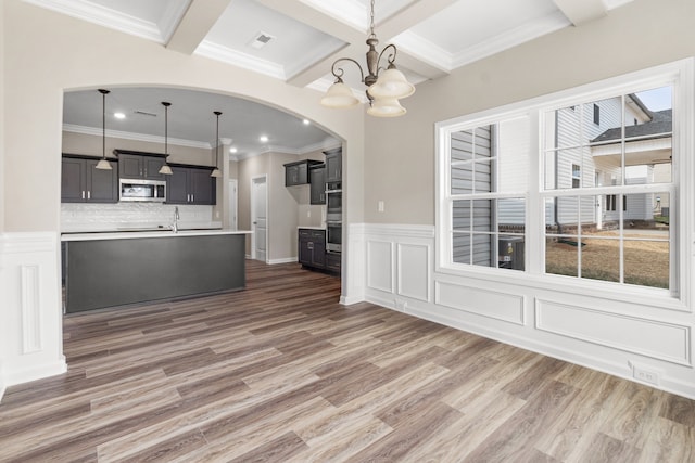 kitchen with an inviting chandelier, stainless steel appliances, hanging light fixtures, and dark wood-type flooring