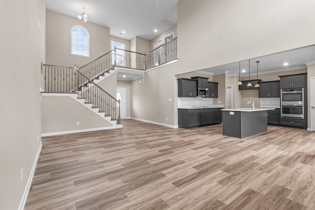 unfurnished living room featuring crown molding, sink, a towering ceiling, and hardwood / wood-style flooring