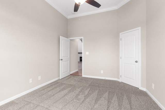 unfurnished bedroom with carpet, a towering ceiling, ceiling fan, and ornamental molding