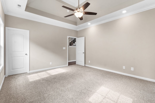 carpeted empty room with a raised ceiling, ceiling fan, and crown molding