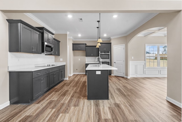 kitchen featuring dark hardwood / wood-style flooring, an island with sink, decorative light fixtures, and appliances with stainless steel finishes