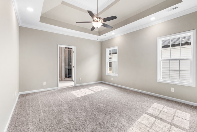 empty room featuring carpet floors, a tray ceiling, ceiling fan, and crown molding