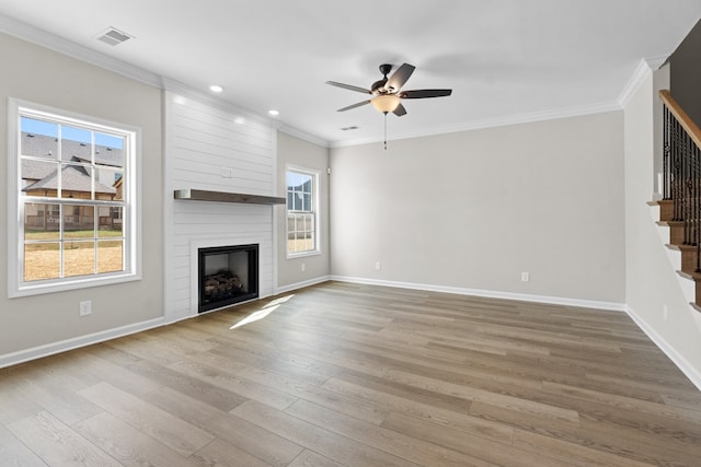 unfurnished living room with ceiling fan, a large fireplace, ornamental molding, and light hardwood / wood-style flooring