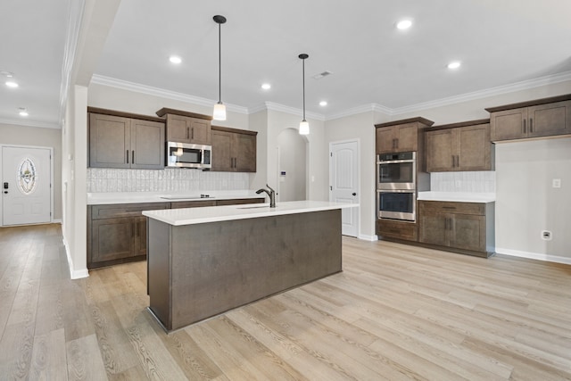 kitchen featuring crown molding, sink, hanging light fixtures, appliances with stainless steel finishes, and light hardwood / wood-style floors