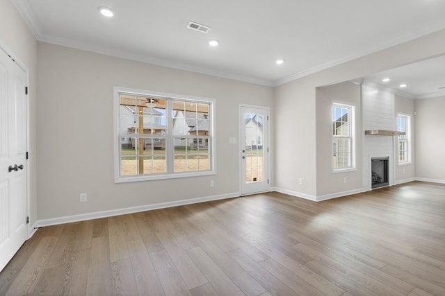 unfurnished living room with a large fireplace, light hardwood / wood-style floors, and ornamental molding