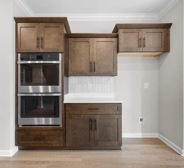 kitchen with light hardwood / wood-style flooring, stainless steel double oven, and ornamental molding