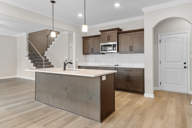 kitchen featuring tasteful backsplash, dark brown cabinetry, sink, light hardwood / wood-style flooring, and hanging light fixtures