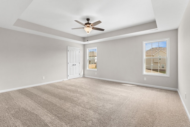 empty room featuring carpet, ceiling fan, and a raised ceiling