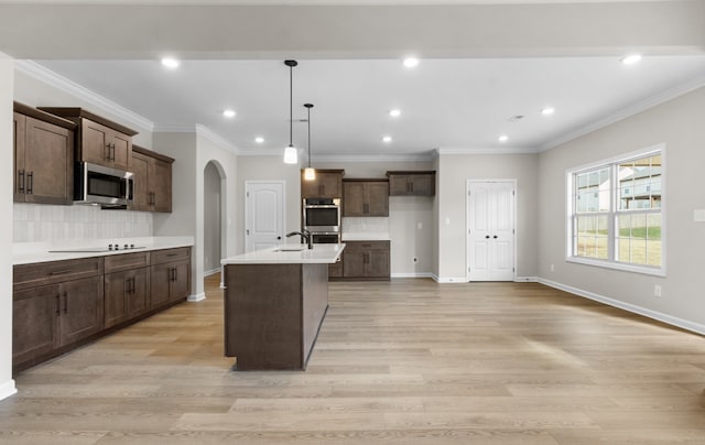 kitchen featuring pendant lighting, sink, light wood-type flooring, an island with sink, and appliances with stainless steel finishes