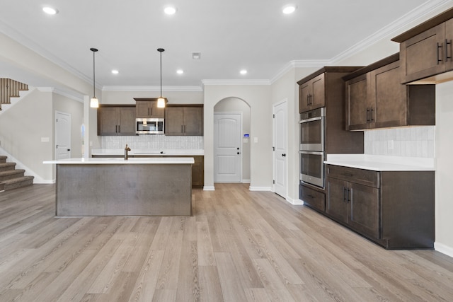 kitchen featuring decorative light fixtures, dark brown cabinets, light wood-type flooring, and appliances with stainless steel finishes