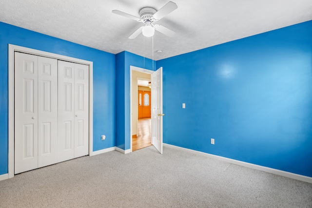 unfurnished bedroom with carpet flooring, ceiling fan, a textured ceiling, and a closet