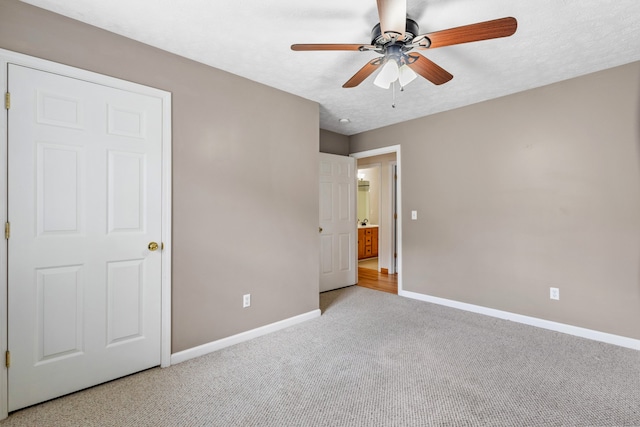 unfurnished bedroom with ceiling fan, light colored carpet, and a textured ceiling