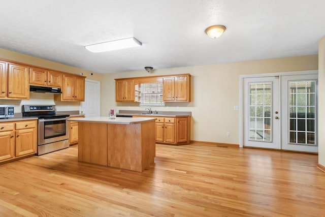 kitchen with french doors, sink, light hardwood / wood-style floors, a kitchen island, and stainless steel appliances