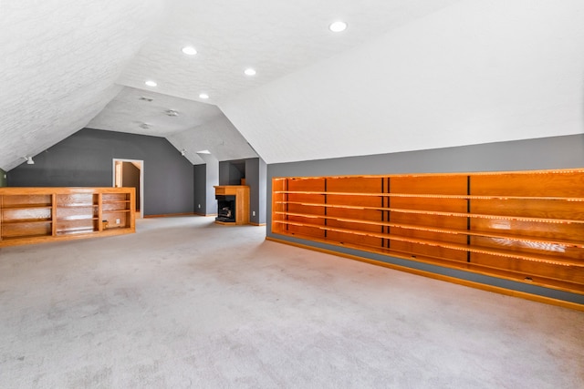 additional living space featuring carpet flooring, lofted ceiling, and a textured ceiling