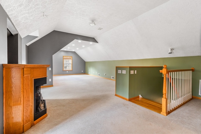 bonus room with a textured ceiling, carpet floors, and vaulted ceiling