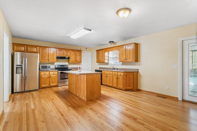 kitchen with light wood-type flooring, a center island, stainless steel appliances, and sink