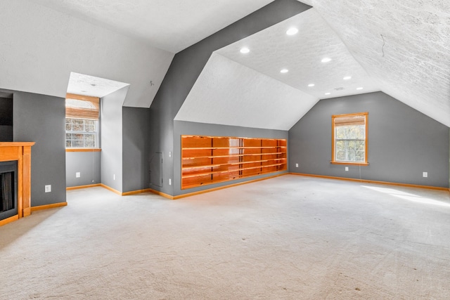 bonus room featuring carpet flooring, built in shelves, a textured ceiling, and vaulted ceiling