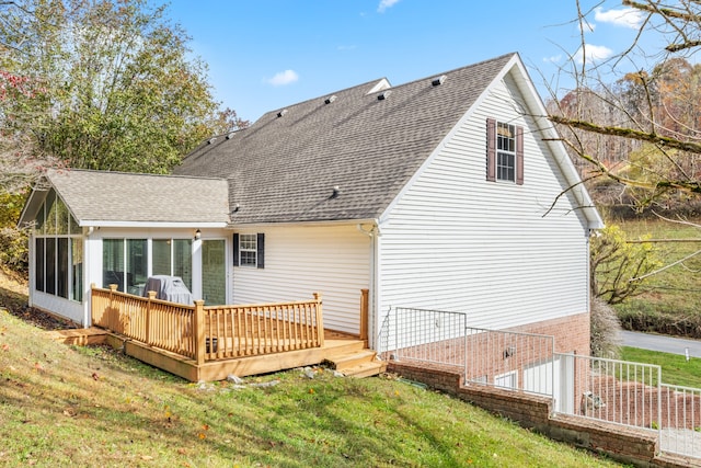 rear view of house with a sunroom, a yard, and a deck