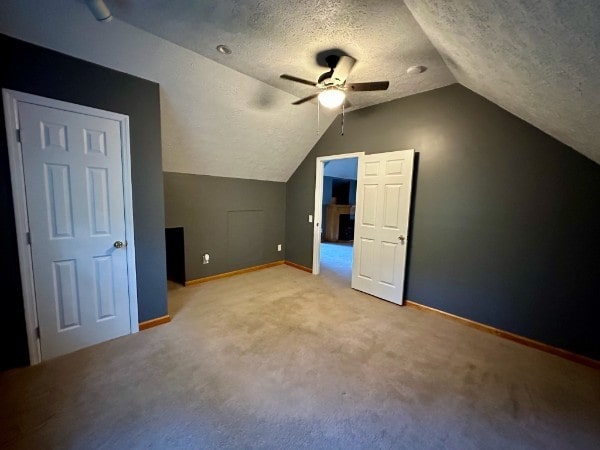 bonus room with ceiling fan, light colored carpet, lofted ceiling, and a textured ceiling