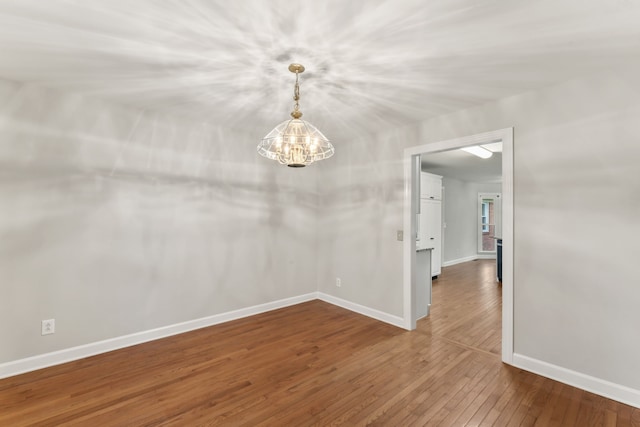 unfurnished room with a notable chandelier and hardwood / wood-style flooring