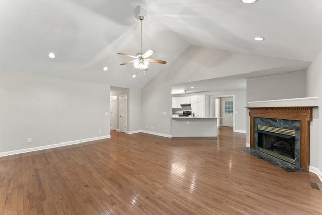 unfurnished living room with ceiling fan, a high end fireplace, high vaulted ceiling, and hardwood / wood-style flooring