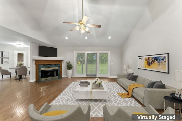 living room featuring hardwood / wood-style flooring, high vaulted ceiling, ceiling fan, and a premium fireplace