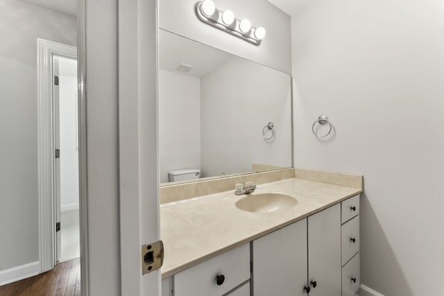 bathroom featuring vanity, wood-type flooring, and toilet