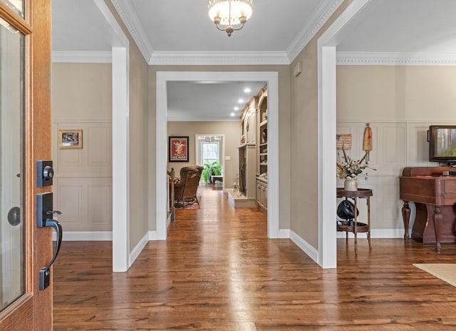 foyer with an inviting chandelier, dark wood-type flooring, and ornamental molding